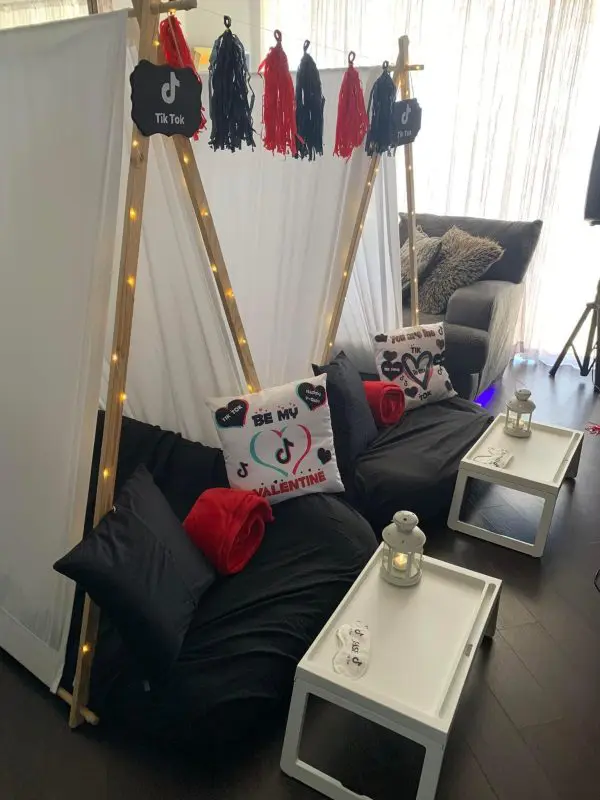 Two teepee tents with "TikTok" signs, black and red cushions, and themed pillows are set up indoors for a fun kids party rental. Each tent includes a small white table and lantern in front, making it perfect for an exciting slime party.