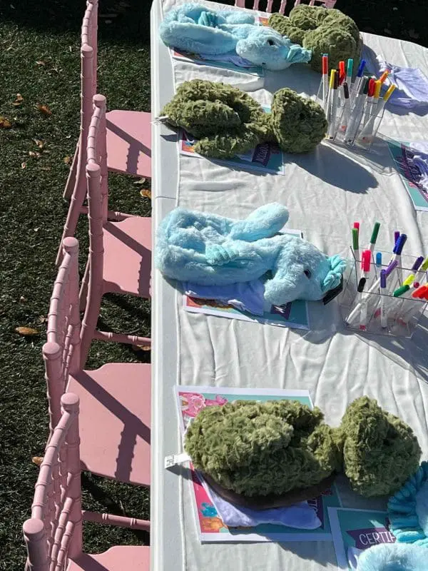 Blue and green plush sea turtles, perfect for a Build A Bear Party, displayed on a table with colored markers and certificates.