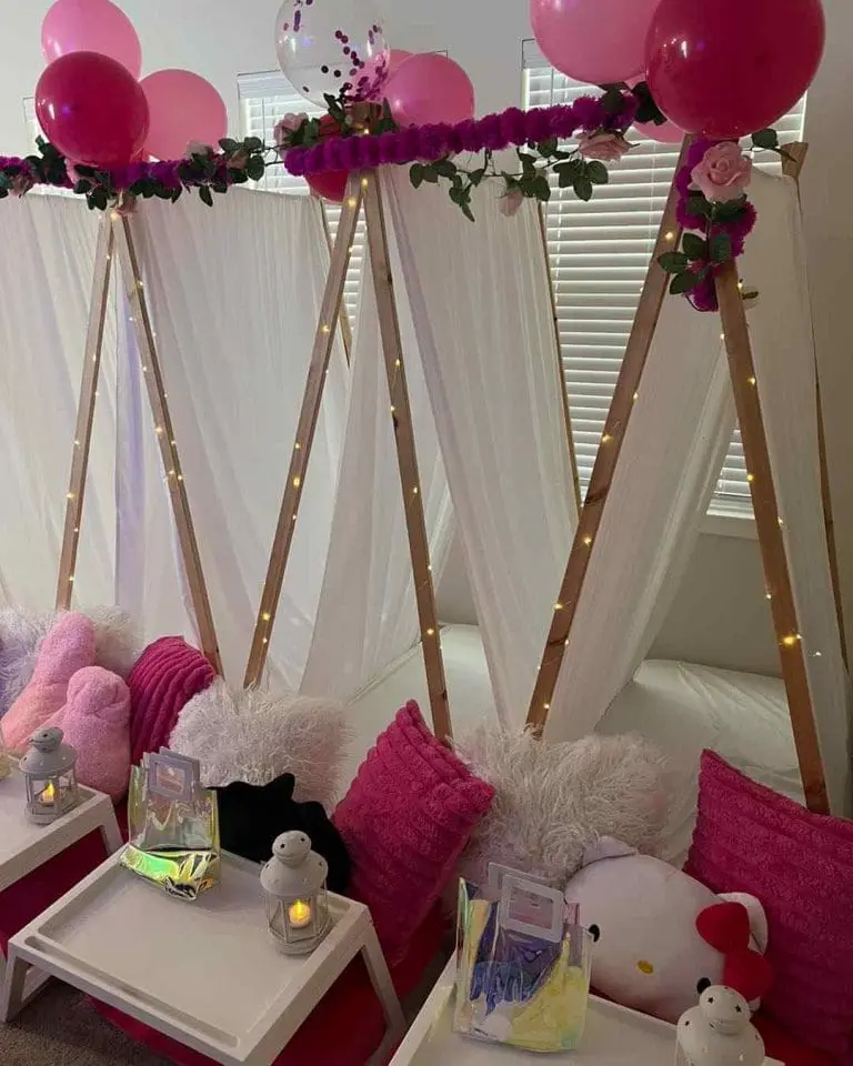 Indoor teepee tents adorned with pink balloons, string lights, and cozy cushions for an Ultimate Slumber Party setup.