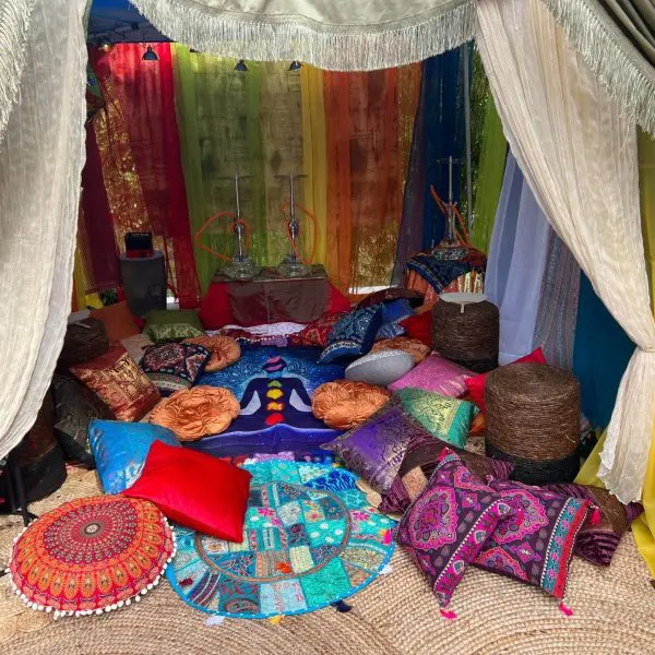 Vibrant Wonderland Wonders lounge setup with colorful curtains, assorted patterned cushions, and a straw mat.