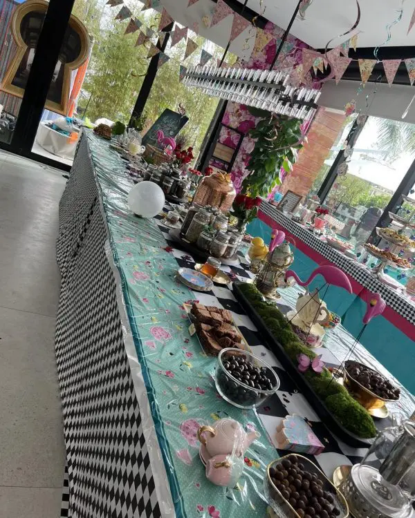 Long table adorned with a mix of sweet treats and decorative items for an Alice in Wonderland party, featuring a festive, colorful setting.