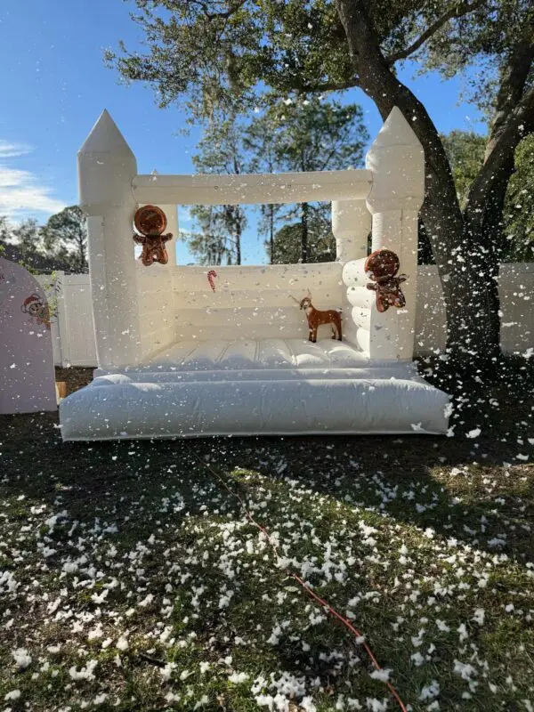 Experience the magic of winter wonderlands with our enchanting outdoor white inflatable bounce house, beautifully adorned with whimsical gingerbread figures and a festive reindeer. Transform your event into a captivating snowy paradise, with scattered faux snowflakes covering the ground, all made possible through Snow Machine Rental's exceptional services. Perfect for holiday parties and events that evoke seasonal cheer and imaginative fun!