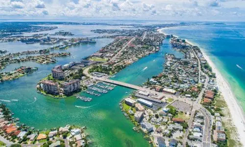 Aerial view of a coastal party in st.pete party rentals. A town with a dense layout, featuring buildings, roads, and surrounding service areas.