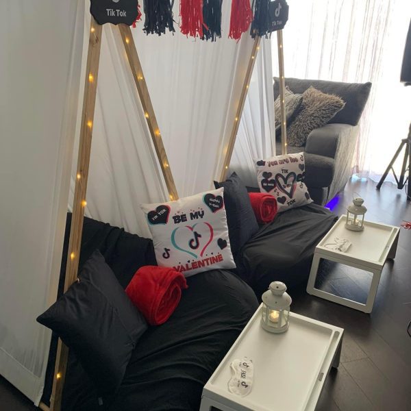 Two teepee tents with "TikTok" signs, black and red cushions, and themed pillows are set up indoors for a fun kids party rental. Each tent includes a small white table and lantern in front, making it perfect for an exciting slime party.