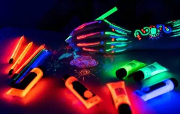 Hand painted with neon colors under blacklight, this setup is perfect for a slime party, surrounded by glowing paint tubes and tools.