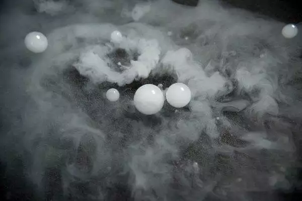 White spheres and swirling mist from a Frogger F4 Bubble Fogger Rental on a textured surface, creating an ethereal atmosphere.