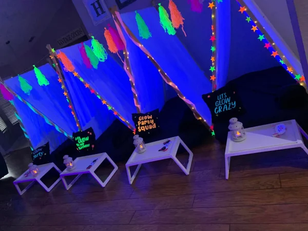 Neon glow party setup with colorful streamers, glowing signs, and small tables with tea light candles in a dimly lit room, hanging on sleepover tents in Orlando, Tampa, Lakeland all the way to Miami.