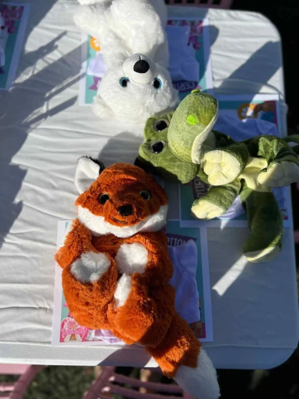 Stuffed toys—a fox, a crocodile, and a white bear—on a sunny table at a kids party in Central Florida.