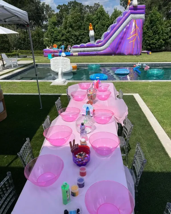 A table set up for a slime making party with a water slide, perfect for pink-themed celebrations in Lakeland, orlando, Tampa, Miami and surrounding areas.