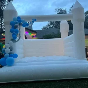 Inflatable white bounce house decorated with blue and white balloons at a Central Florida event during dusk.