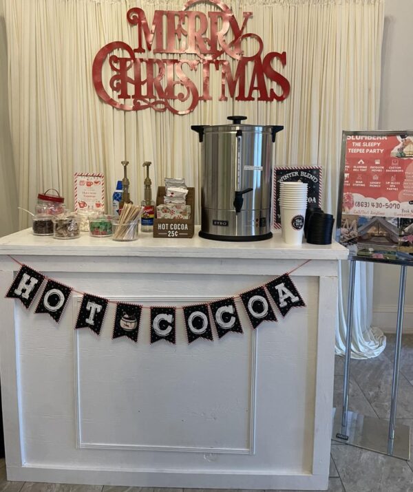 Experience the ultimate Camping Party Theme with a charming hot cocoa stand, complete with a vintage-style dispenser and a selection of rustic cups. Adorned with festive Christmas decorations, this cozy setup exudes warmth and holiday cheer. A whimsical sign reading "Hot Cocoa 25¢" invites guests to savor deliciously affordable warmth at your gathering. Perfect for holiday get-togethers or cozy camping-themed parties, this inviting cocoa station combines nostalgia and seasonal charm for an unforgettable celebration experience. Discover how to craft the perfect ambiance for your next winter event!.