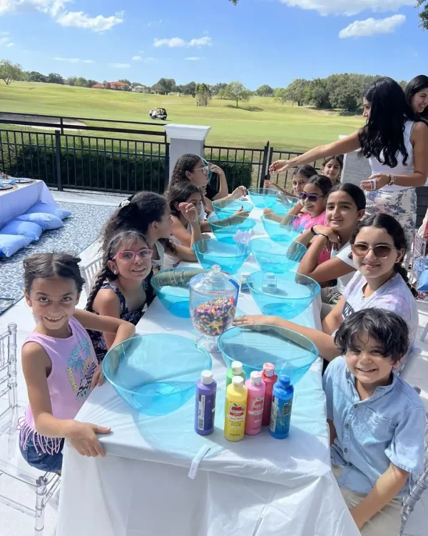 Children engaging in a craft activity at a Sicilian Themed Party, with colorful supplies and a sunny backdrop.