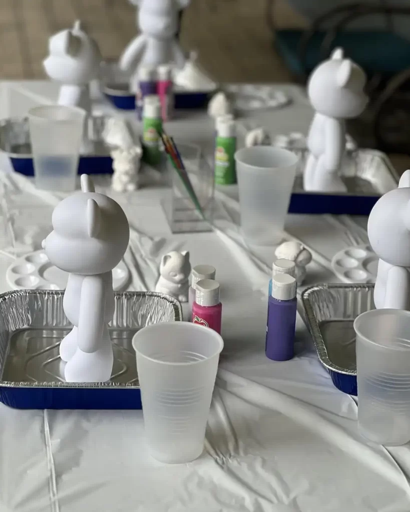 Barbie Themed Party vinyl figures on trays with paint bottles and cups, arranged for a Barbie themed painting workshop.