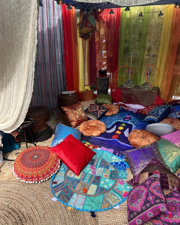 Colorful, bohemian-style tent interior filled with vibrant cushions, rugs, and draped fabrics creating a cozy, eclectic ambiance fit for an Alice in Wonderland party.