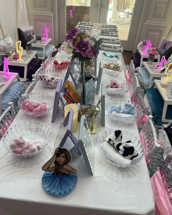 A table set up for a themed children's Spa Party with DIY lip Gloss, featuring neon decorations, books, flowers, and plush toys.