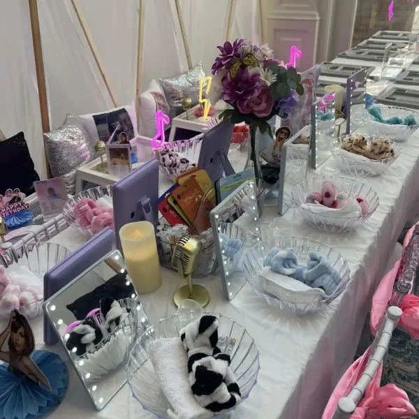 Transform your spa party into a stunning display with mirrors, LED lights, bowls filled with towels and hairbands, and vibrant party decorations featuring flowers and music note symbols. Ideal for hosting a Spa Party with the exciting DIY Lip Gloss station!