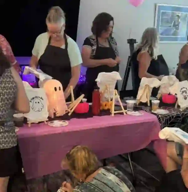 Join the ultimate Crafty Onesie Painting Party at your Halloween-themed baby shower, where creativity and imagination take center stage! Under bright, cheerful lights that highlight the festive pink cloth-covered tables, participants don aprons and unleash their artistic flair. Watch as guests transform ordinary onesies into delightful Halloween decorations with charming ghost and adorable pumpkin designs. This lively event promises a colorful explosion of artistic expression, perfect for celebrating your new arrival in a spirited atmosphere brimming with creativity and excitement. Ideal for crafting enthusiasts seeking a memorable experience full of vibrant energy, this party is sure to enchant every attendee!