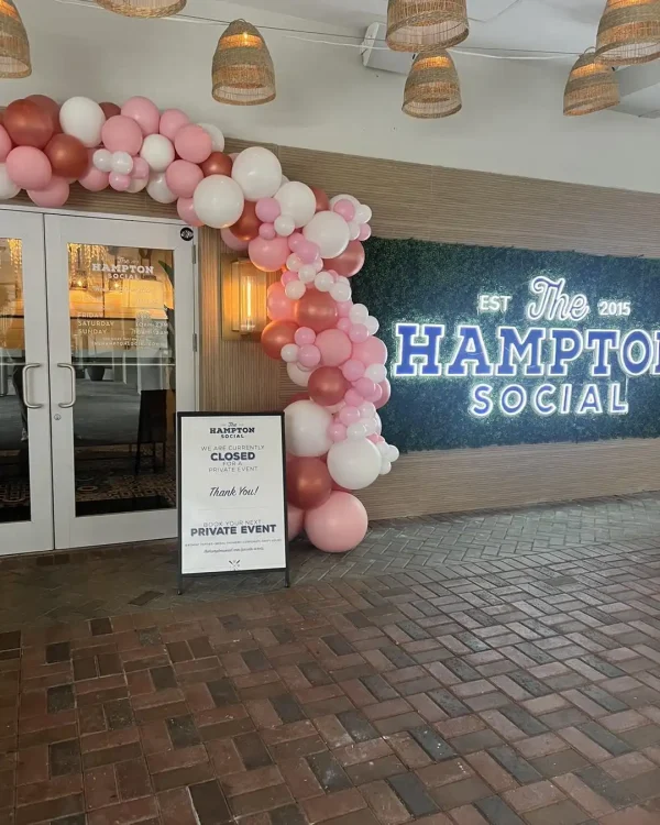 The entrance of The Hampton Social features a pink and white balloon arch. A sign reads "Closed for a Private Harry Potter Themed Party." The neon establishment sign and brick pavement are visible, setting the stage for a magical Harry Potter celebration inside.