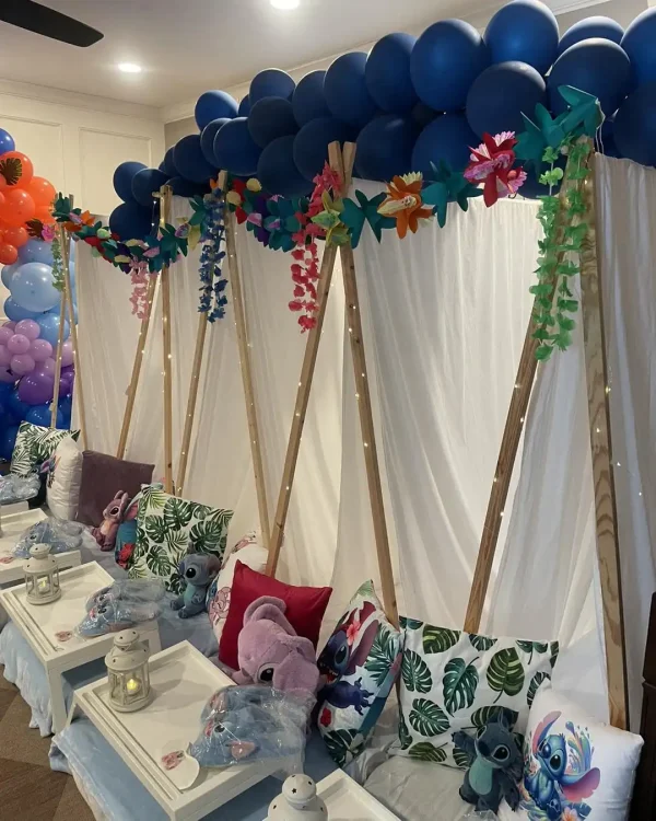 A row of indoor tents with tropical-themed pillows, floral garlands, and Stitch plush toys set the stage under a canopy of blue balloons for a magical Harry Potter Themed Party.