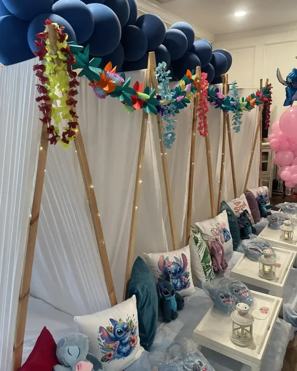 A party setup with teepee tents, decorated with blue balloons, colorful leis, and Harry Potter Themed Party-themed pillows. Tables are set up with lanterns, Harry Potter Themed Party plushies, and gift bags. It’s a magical mix that feels like a cross between a Hawaiian luau and a Harry Potter party.