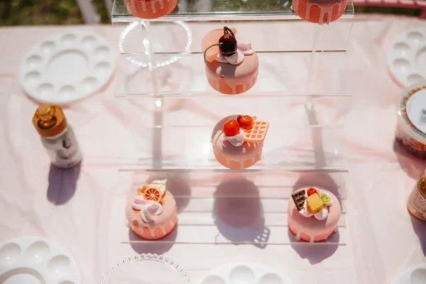 Showcase an array of small, decorated cakes and desserts on a multi-tiered clear stand with the Cupcake Decorating Party. Perfect for any celebration, each delightful cupcake is adorned with various toppings like fruit slices, chocolates, and pastries.