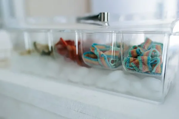 Close-up of a clear compartmentalized container filled with ice, showcasing colorful items resembling small bowls or scoops, reminiscent of the Slushy/Margarita Bar Package, placed on a white surface.