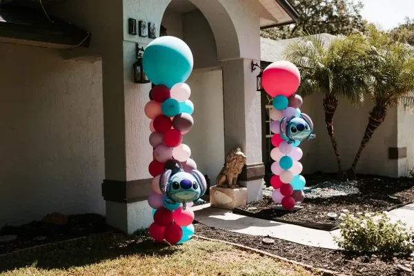 Two balloon columns adorned with Stitch-themed balloons stand at the entrance of a house, creating the perfect setting for unforgettable memories. Capture these vibrant decorations with our Event Photography Packages, ensuring every detail is beautifully preserved.