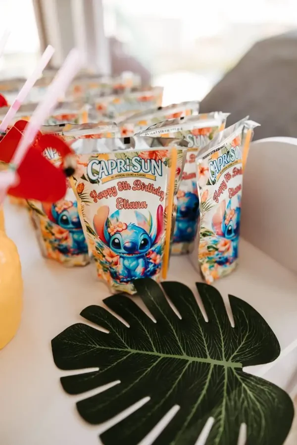 Several "Happy 8th Birthday" Capri-Sun juice pouches with a tropical theme featuring a cartoon character are displayed on a table alongside a large green leaf decoration, creating the perfect setting for capturing memorable moments with our Event Photography Packages.