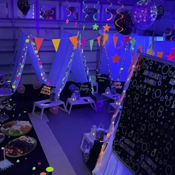 Immerse yourself in the ultimate neon-themed slumber party extravaganza, where vibrant black lights transform the room into a dazzling spectacle. Eye-catching, colorful pennant banners and radiant star decorations illuminate the night with luminous brilliance. Slumberr’s enchanting tent-like structures glow with captivating, glow-in-the-dark accents that invite sleepover fun. A feast for the senses awaits on a table laden with an array of delicious foods, creatively labeled with neon tags that pop against a backdrop of glowing balloons suspended in midair. A charming message board proudly announces "Happy 12th Birthday," adding a personal touch to this unforgettable glow party experience. This scene is perfect for those seeking innovative slumber party ideas filled with excitement and creativity!