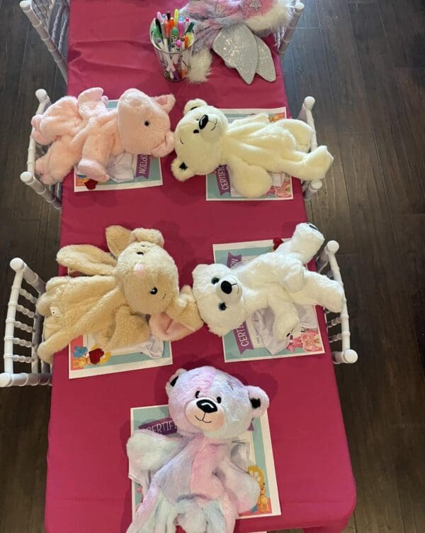 A charming display featuring an assortment of plush teddy bears and vibrant craft supplies meticulously arranged on a soft pink tablecloth, accompanied by award certificates, sets the stage for an engaging and creative activity. This delightful setup promises a captivating afternoon filled with hands-on crafting fun and bear-themed adventures. Perfect for children's events or DIY enthusiast gatherings, this scene captures the essence of creativity and playful imagination.