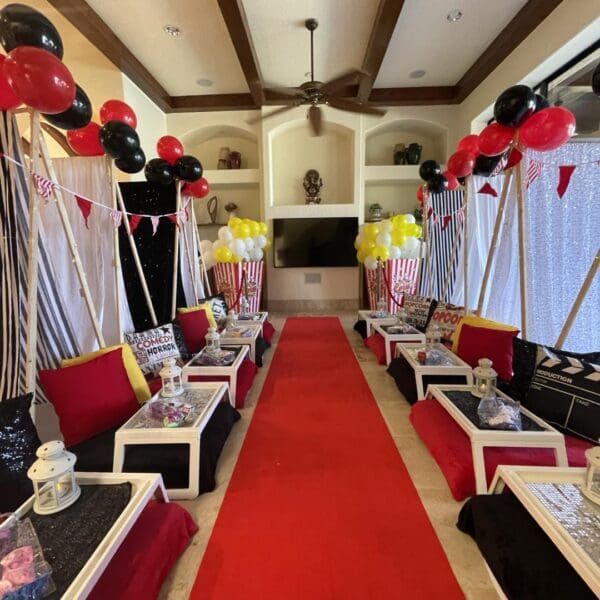 Step into a Hollywood-inspired movie-themed party room, lavishly decorated to transport you straight to the glitz and glamour of the silver screen. A plush red carpet welcomes guests in true celebrity style, setting the scene for an unforgettable cinematic experience. Eye-catching black and red balloons float above, adding pops of drama and excitement throughout the space. Cozy up with an array of decorative movie-themed pillows featuring iconic film reels, clapperboards, and popcorn motifs—perfect for creating that ultimate blockbuster ambiance. Ideal for any film fanatic or those looking to host an Oscar-worthy celebration!