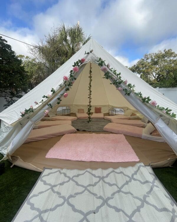 Explore the enchanting setup of our Movie Concession Stand Rental with its charming white tent, reminiscent of a classic concession stand. This delightful venue is adorned with vibrant pink flowers and nestled on lush green grass, providing a picturesque setting for events. Step inside to find cozy cushions and stylish rugs that create an inviting atmosphere perfect for gathering and relaxation. Ideal for outdoor movie nights or special occasions, this concession stand rental combines elegance with comfort in a scenic environment.